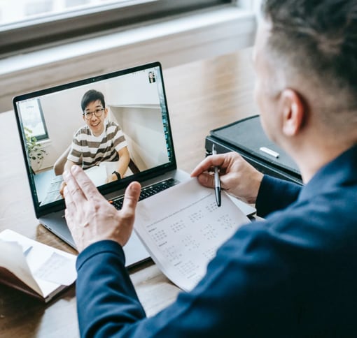 A man on a video call with a note pad in front of him, the photo is taken from over his shoulder