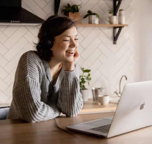 a smiling woman looking at a laptop on a video call 